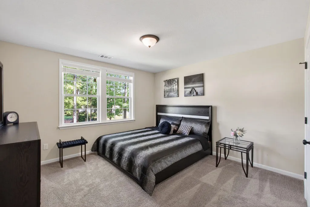 A well-lit bedroom with soft carpet offers a serene retreat.
