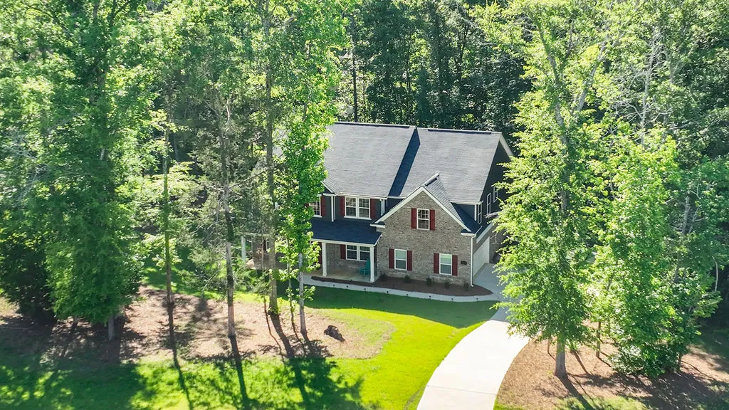 A private, brick-front home nestled among verdant trees offers serene living.