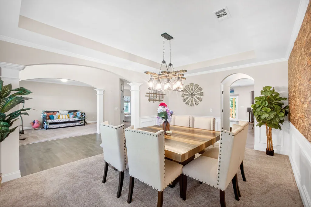 Step into this elegant dining area, boasting crown molding, a decorative chandelier, and rich carpet flooring.