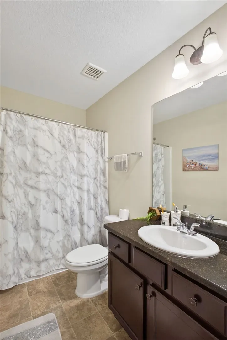 Functional bathroom featuring a single vanity and a shower with a marble-patterned curtain.