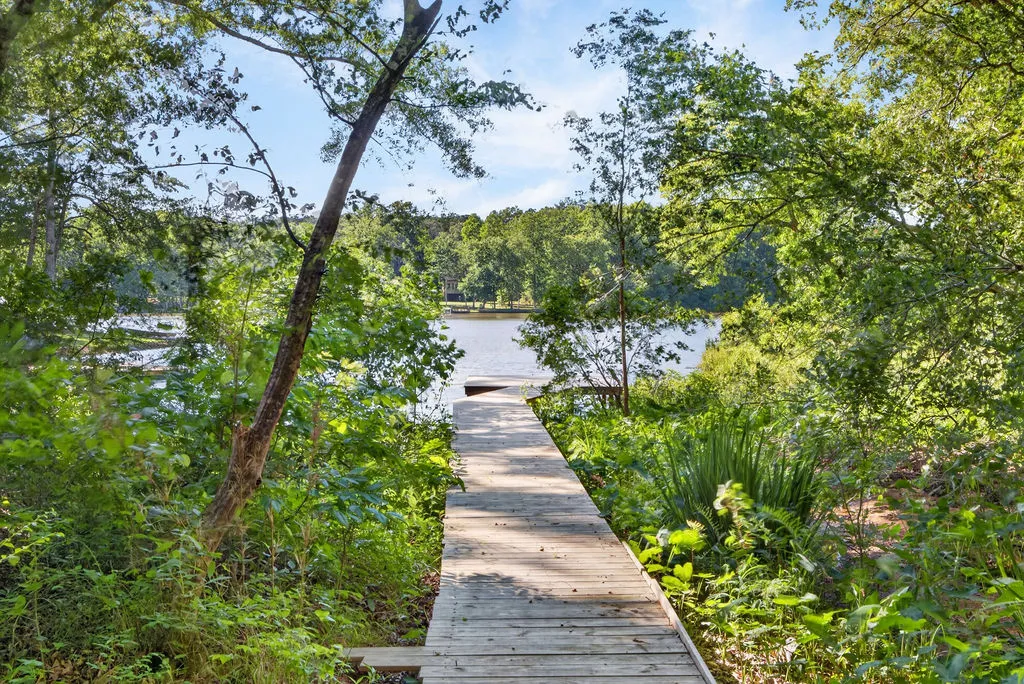 A tranquil wooden pier extends into the serene lake, enveloped by verdant foliage.