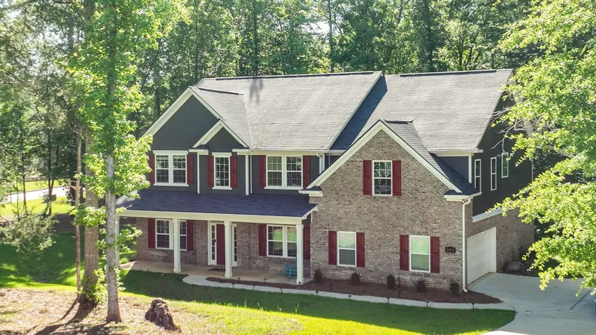 A classic brick and siding home, offering a welcoming porch, mature landscaping, and ample driveway space.