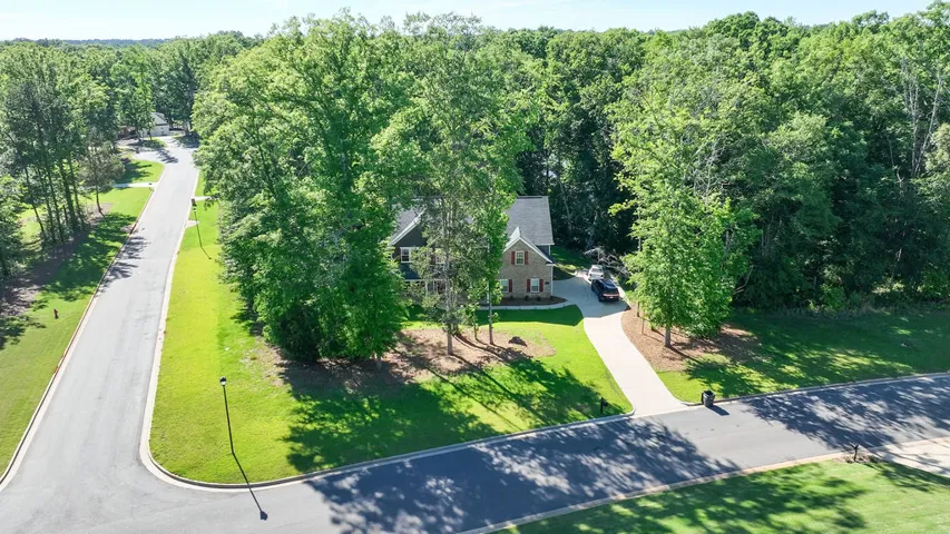 An aerial perspective reveals a charming residence nestled amidst a vibrant, treelined landscape.