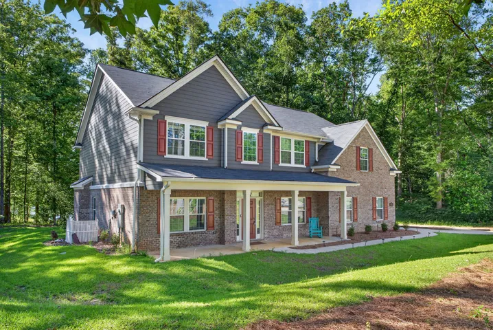 A classic brick and siding residence with a welcoming front porch, nestled amidst a lush, wooded landscape.