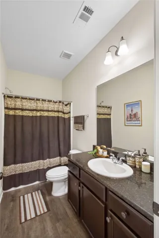 A compact bathroom featuring a rich espresso vanity and sleek dark countertops, optimizing space with refined style.