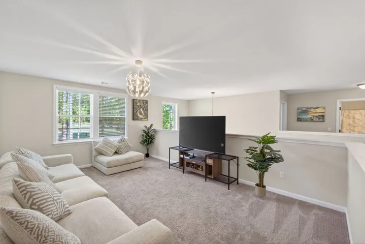 A generous loft offers a comfortable gathering space with plush carpet underfoot.