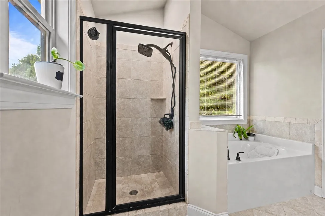 The soaker tub is tucked beneath the window with a separate tiled shower next to it.