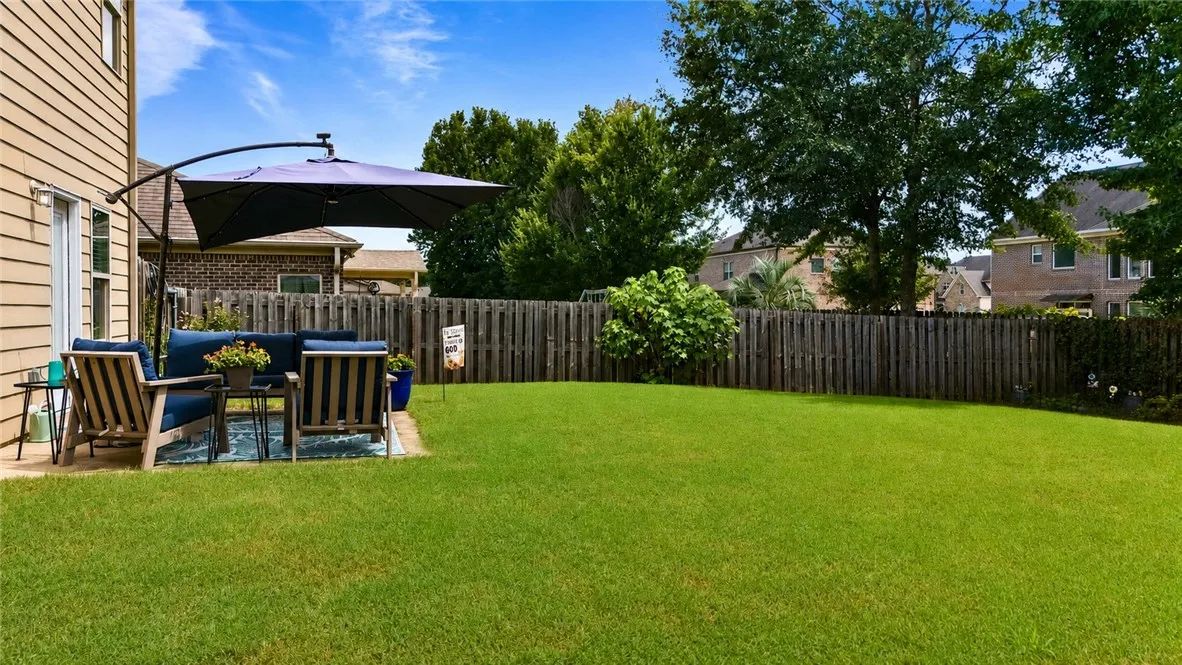 Out back, a spacious fenced yard offers plenty of room to enjoy the outdoors, with a patio for seating, blueberry bushes, a peach tree, a passionfruit vine, roses, azaleas and hydrangeas.