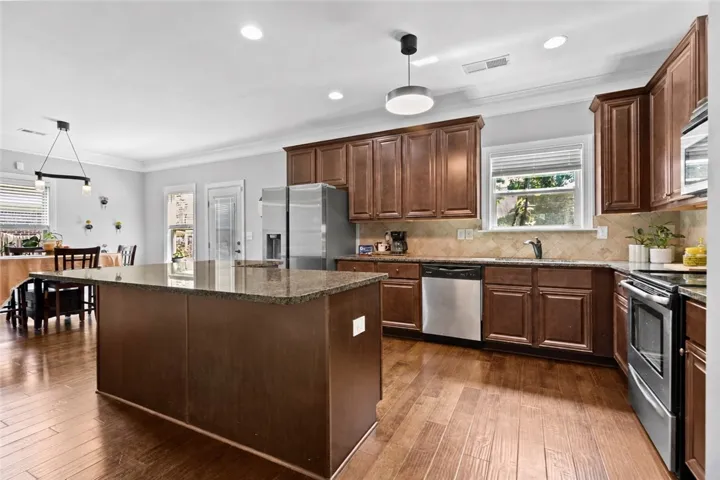 The kitchen features a large center island, rich wood cabinetry, granite countertops, stainless appliances and an adjoining breakfast  area.