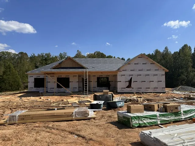 A new construction single-story home takes shape under clear blue skies.