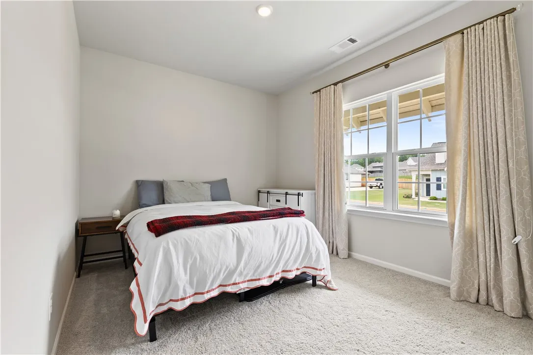This cozy second bedroom features plush carpeting and a bright window, offering comfort and natural light. Easy access from bedroom to second bathroom.