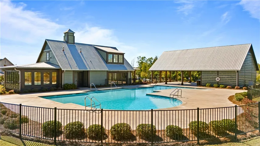 An inviting community swimming pool sparkles under blue skies, flanked by an attractive modern clubhouse with fitness center.