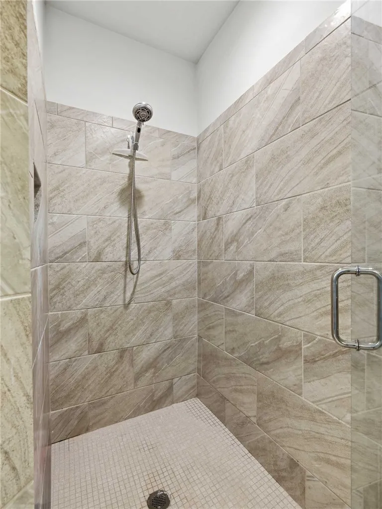 The shower features two complementary tiles and a sleek frameless door.