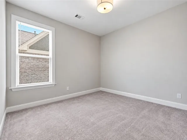 Plush carpeting and a classic sash window define this versatile secondary bedroom space.