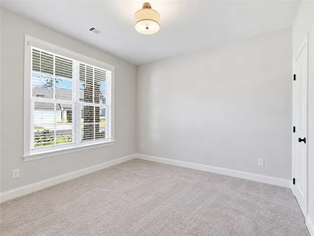 Plentiful natural light fills this versatile room featuring soft neutral carpet and large multi-pane windows.