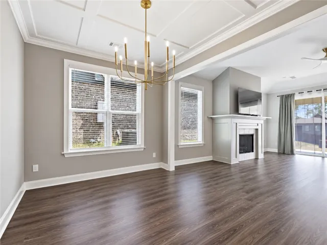 An elegant fireplace anchors the open-plan layout, flanked by tall windows and coffered ceilings.