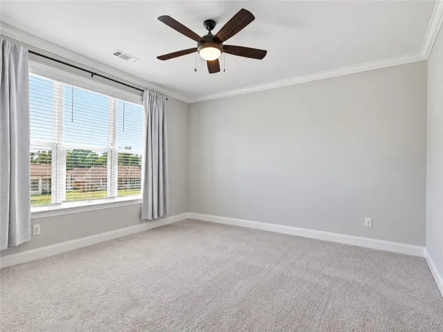 Plush carpeting and classic crown molding frame this versatile bedroom space.