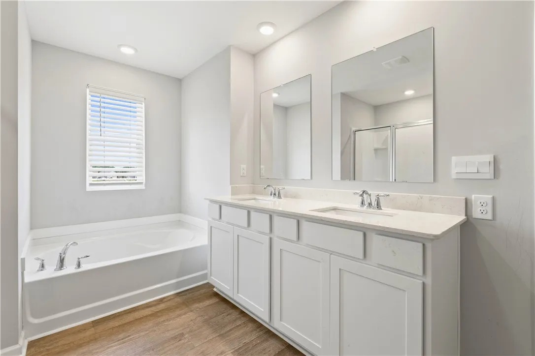 Primary featuring tub, double vanities and tons of natural sunlight