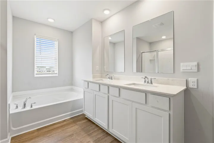 Primary featuring tub, double vanities and tons of natural sunlight