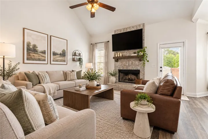 Living room showcases vaulted ceilings and a wood burning fireplace - the perfect place to cozy up this fall! Staging in photo is AI generated for visualization purposes.
