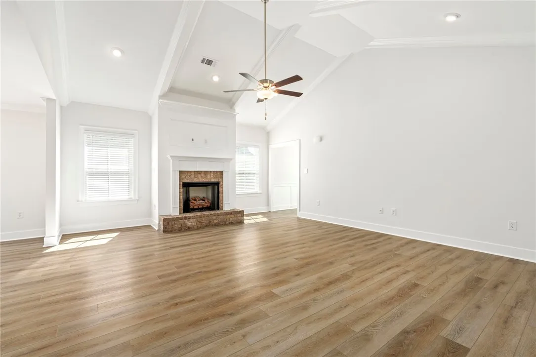 Soaring vaulted beam ceiling, beautiful flooring, ceiling fan and fireplace