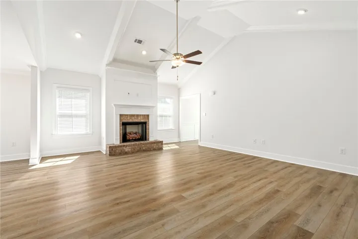 Soaring vaulted beam ceiling, beautiful flooring, ceiling fan and fireplace