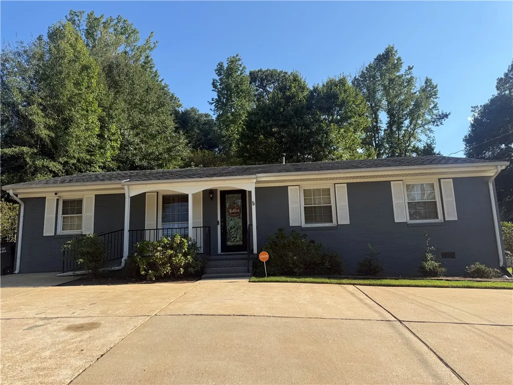 Mature trees frame a classic single-story brick facade complete with a wide concrete driveway.