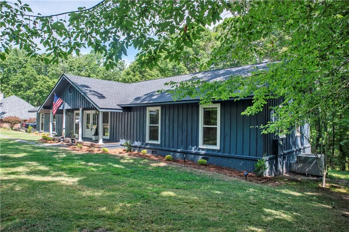 Lush mature trees frame this modern ranch-style home featuring classic board and batten siding.