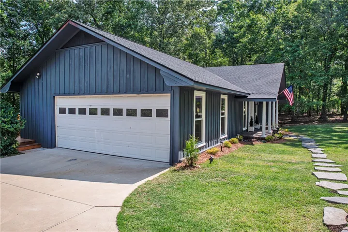 A concrete driveway leads to the attached garage of this board and batten sided home.