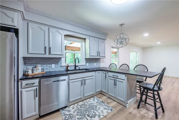 An open kitchen layout features clean cabinetry, classic crown molding, and a built-in breakfast bar.