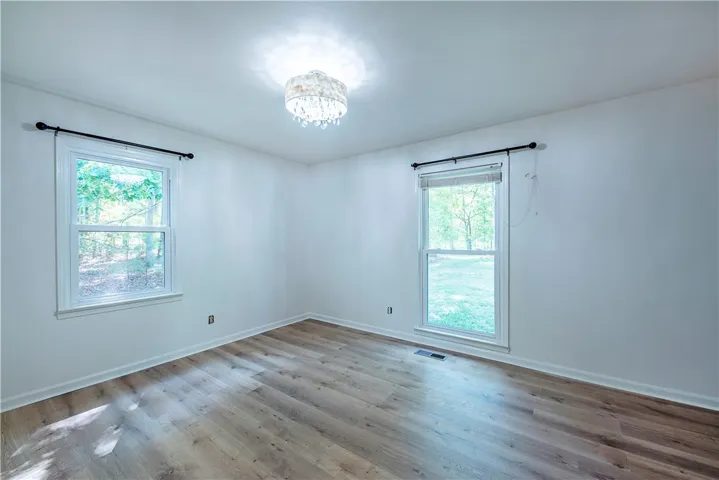 Polished wood-style floors and a classic light fixture define this versatile bedroom space.
