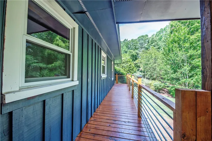 A wooden deck overlooks lush forest views along the side of the home.