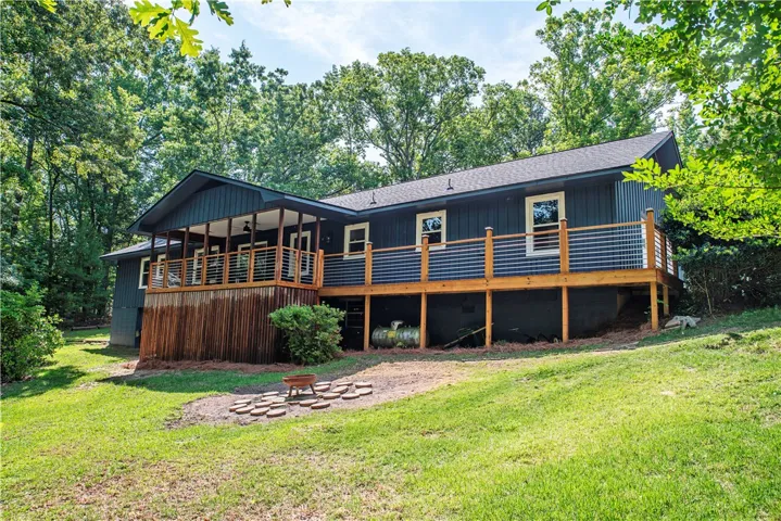 A spacious wooden deck overlooks the grassy yard surrounded by mature trees.