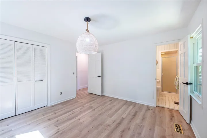 Smooth wood floors and tall windows define this peaceful bedroom with an attached bath.