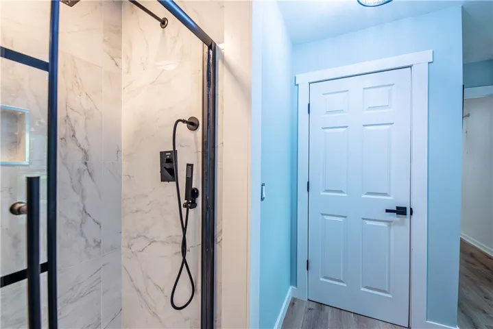 A modern walk-in shower features elegant tile surrounds and sleek black hardware fixtures.