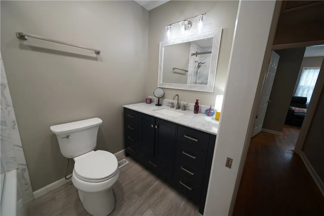 Smooth stone countertops and wood-look flooring define this updated bathroom space.
