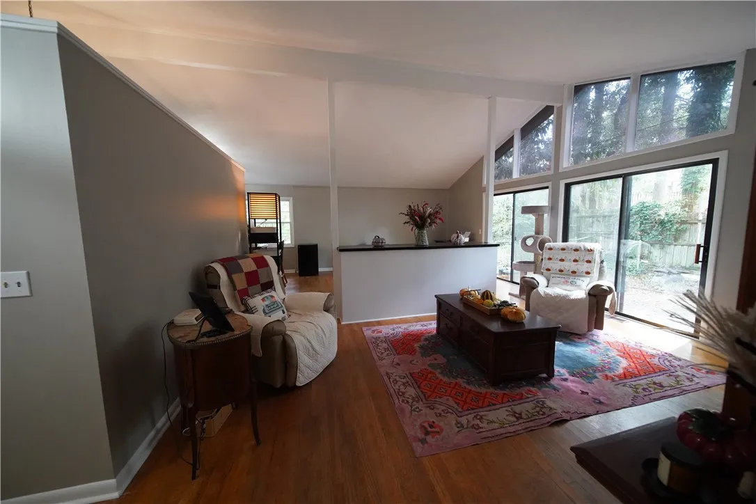 Soaring vaulted ceilings and sliding glass doors maximize natural light across the hardwood floor.