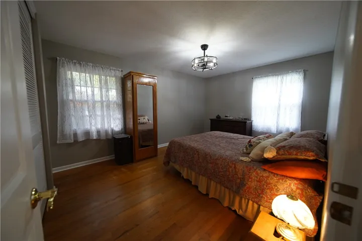 Rich hardwood flooring anchors this cozy bedroom under a smooth ceiling with ample natural light.