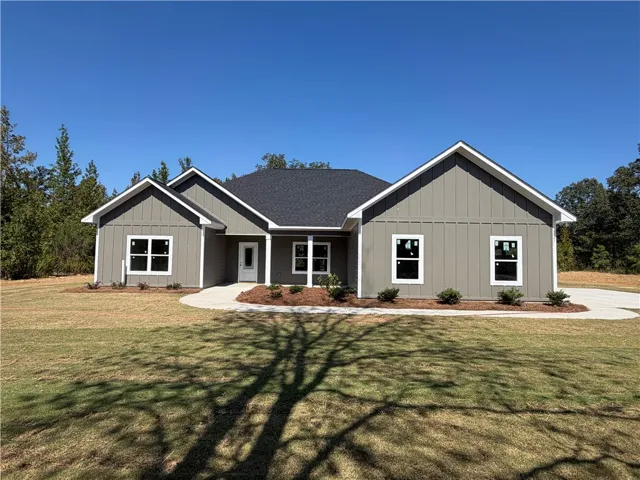 Crisp gables and vertical siding define this modern ranch-style exterior under a clear blue sky.