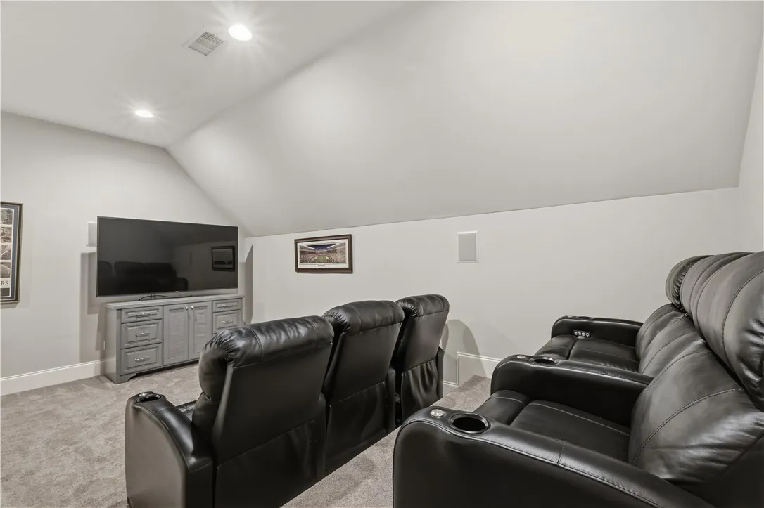 The theater room is designed for gathering, with tiered seating arranged for a comfortable hangout space.
