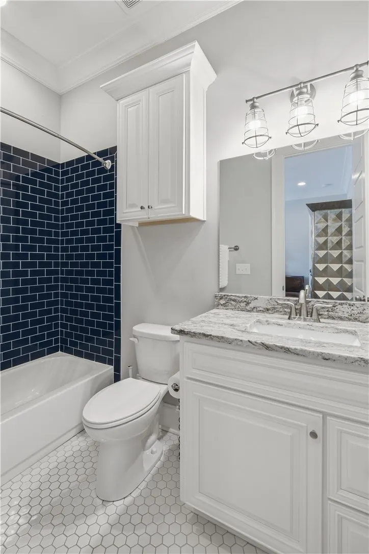 Bath two features honeycomb tile flooring, dark subway tile, and practical storage.