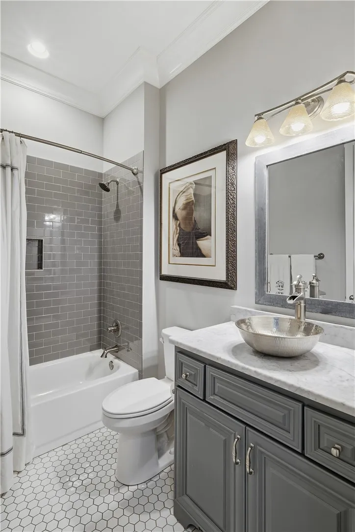 Bath three also features honeycomb tile with coordinating cabinetry and tile surround. It serves bedroom three as well as the common areas.