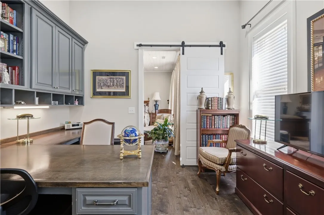 The study is tucked away beyond the primary bedroom. It features a partner's desk and a wall of cabinetry.