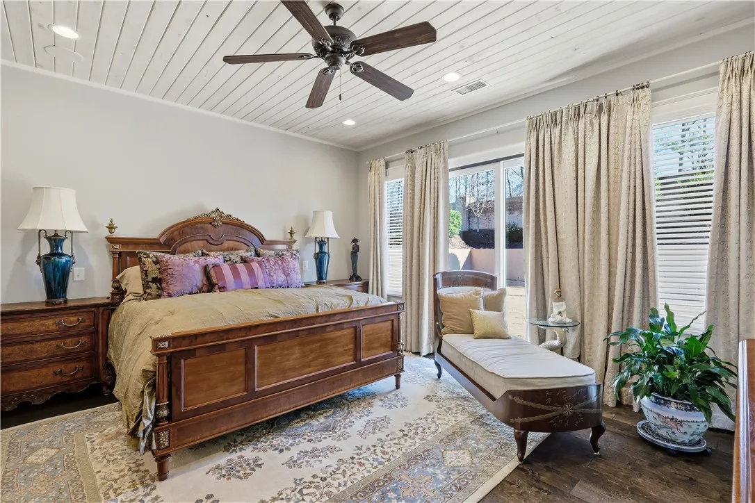 Wood flooring carries into the primary bedroom, highlighted by a wood ceiling and a wall of windows overlooking the rear yard.