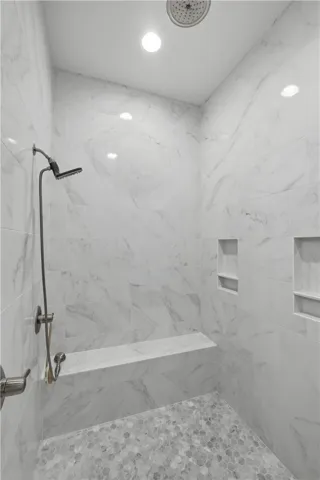 The zero-entry shower features floor-to-ceiling tile, a full-width bench, and multiple niches for toiletries.