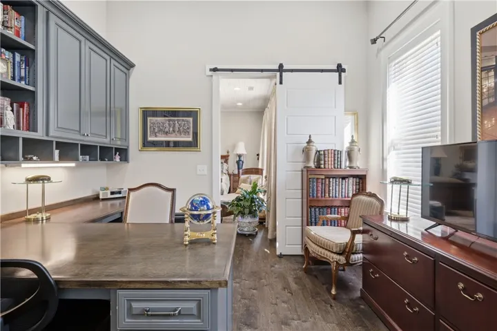 The study is tucked away beyond the primary bedroom. It features a partner's desk and a wall of cabinetry.