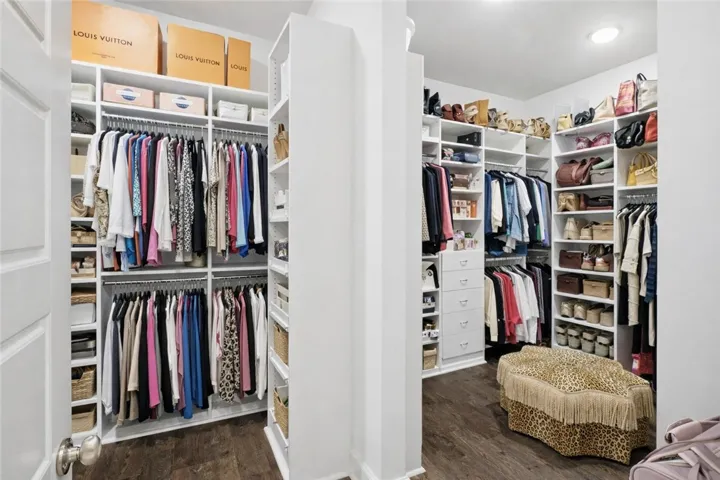 Expansive walk-in closet featuring custom shelving, abundant hanging space, built-in drawers, and dedicated storage for shoes and handbags.