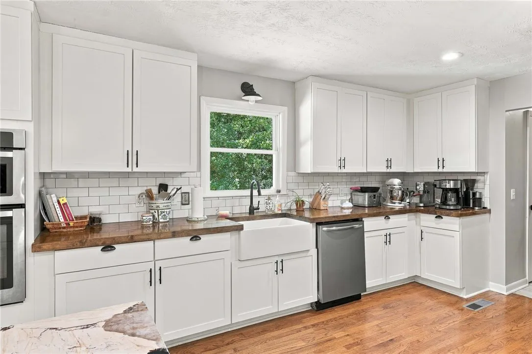 Rich wood countertops contrast beautifully with classic white cabinetry and hardwood flooring.
