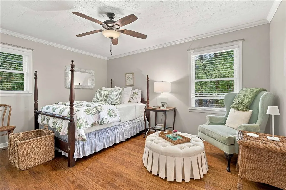 Rich hardwood floors and classic crown molding elevate this serene and comfortable bedroom space.