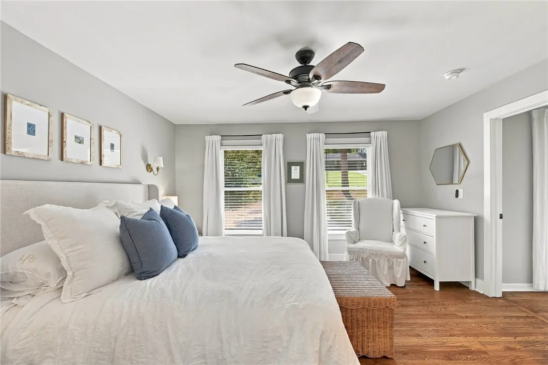 Rich hardwood flooring complements the smooth walls and abundant natural light in this spacious bedroom.